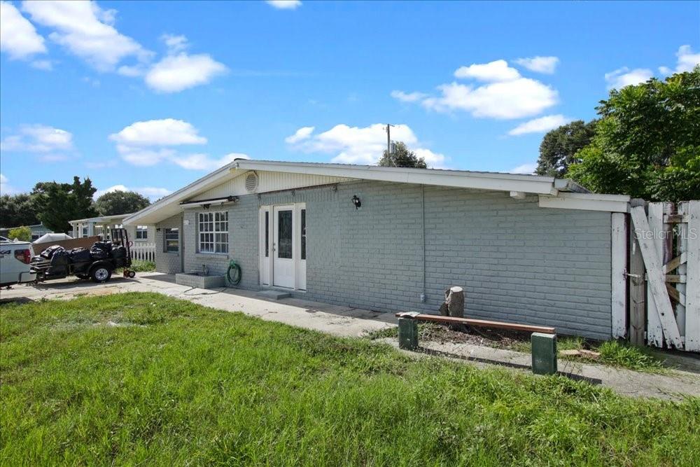 A gray brick house exterior with a white door and a side yard — 2256 SMATHER CIRCLE S, MELBOURNE, FL