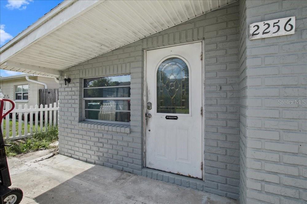 The exterior of a house features a gray brick facade, a white door, and a porch — 2256 SMATHER CIRCLE S, MELBOURNE, FL