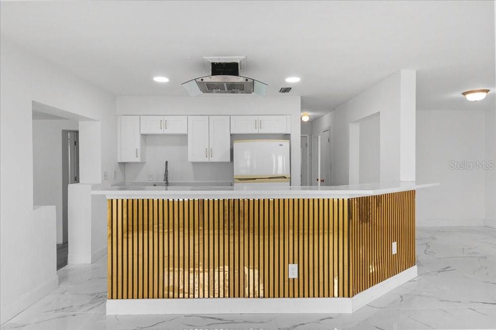 A kitchen features white cabinets, a white refrigerator, and a gold-slatted breakfast bar island — 2256 SMATHER CIRCLE S, MELBOURNE, FL