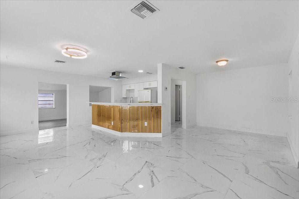 A bright, open-concept living and kitchen area features white marble-look tile floors and a gold-slatted island — 2256 SMATHER CIRCLE S, MELBOURNE, FL