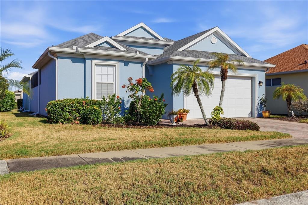 A light blue single-story house features a two-car garage, a front lawn, and palm trees — 586 EDEN DRIVE, ENGLEWOOD, FL