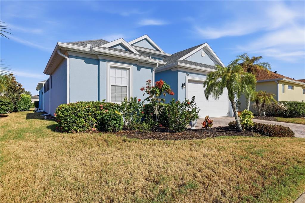 A light blue single-story house features a white garage door and a landscaped front yard — 586 EDEN DRIVE, ENGLEWOOD, FL