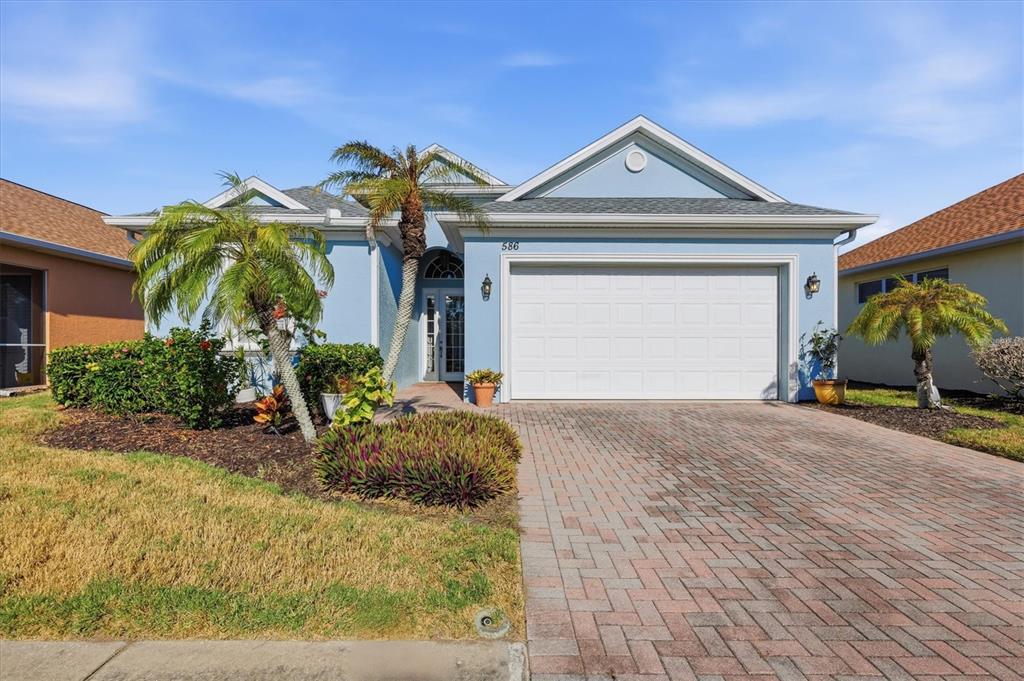 A light blue single-story house features a two-car garage and a brick paver driveway — 586 EDEN DRIVE, ENGLEWOOD, FL