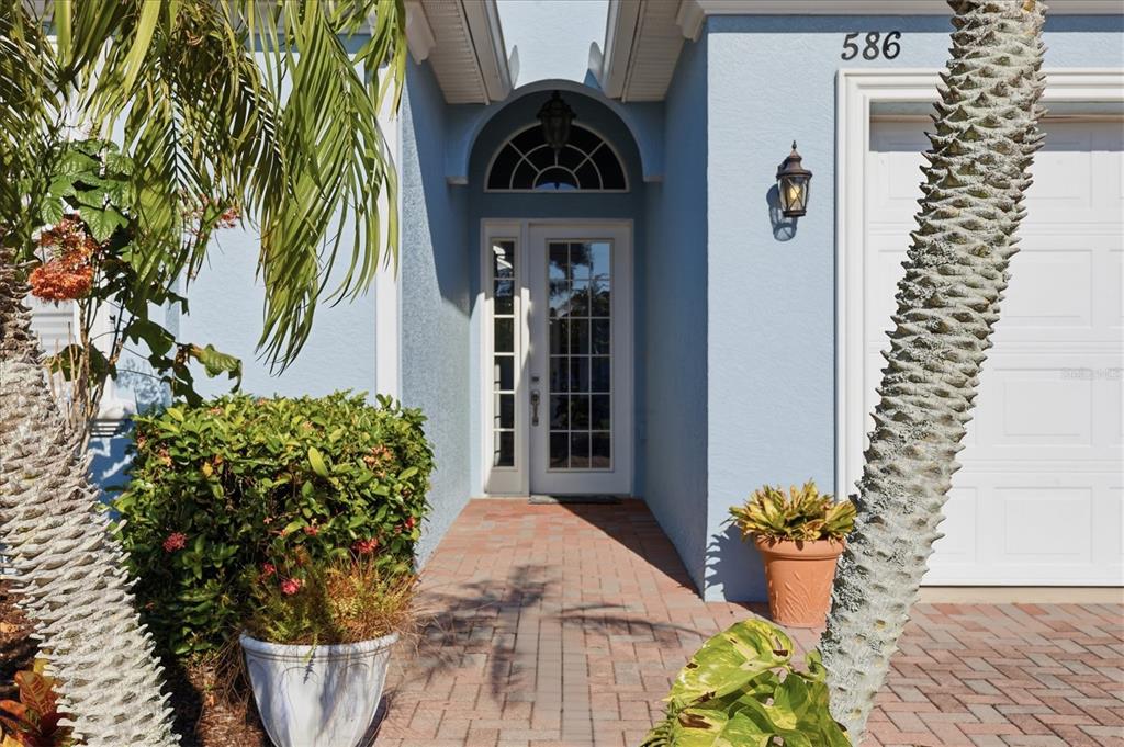A blue house exterior features a brick walkway leading to a glass-paned front door — 586 EDEN DRIVE, ENGLEWOOD, FL