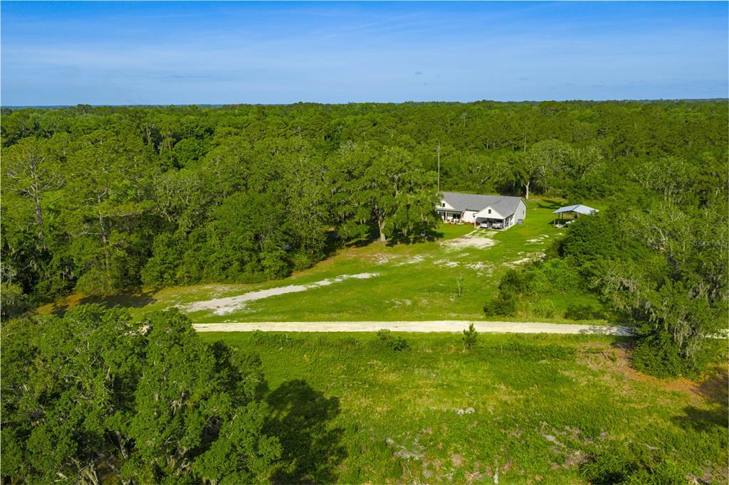 An aerial view shows a house and a detached carport on a large, wooded lot — 5149 SW 119TH PLACE, LAKE BUTLER, FL