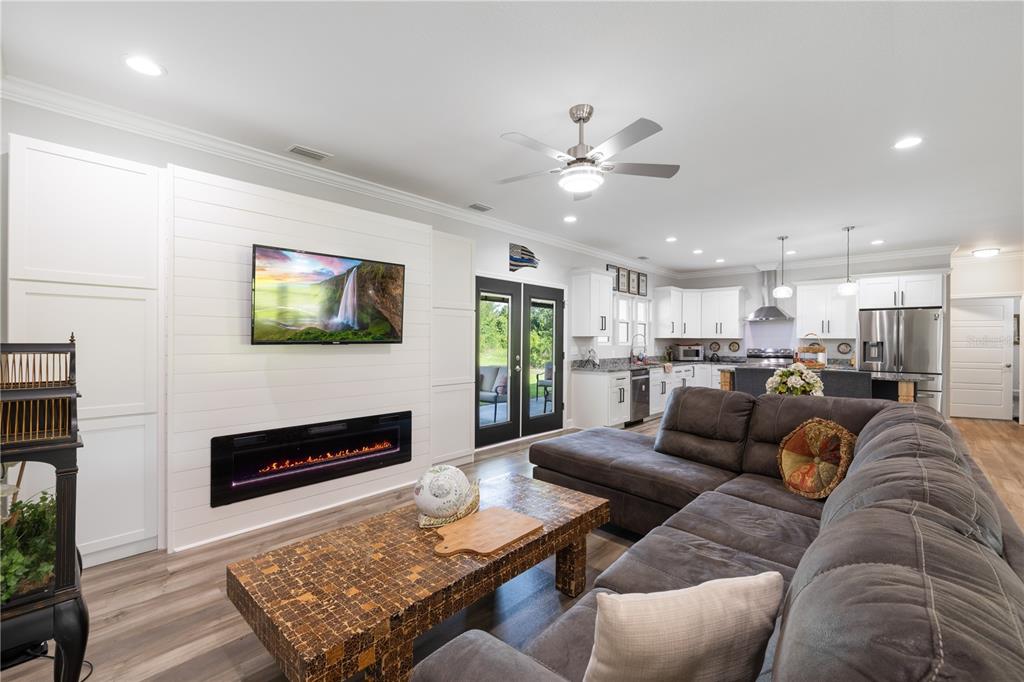 A living room with a shiplap fireplace wall, sectional sofa, and an open-concept kitchen — 5149 SW 119TH PLACE, LAKE BUTLER, FL