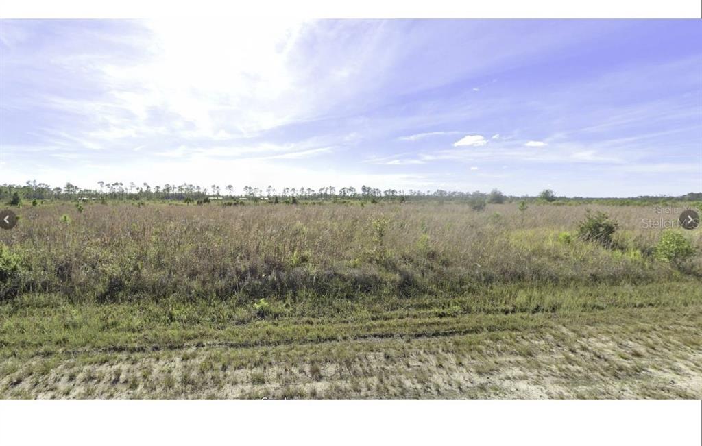 A wide, flat, grassy field under a bright blue sky with scattered clouds — CALLIANDRA DRIVE, INDIAN LAKE ESTATES, FL