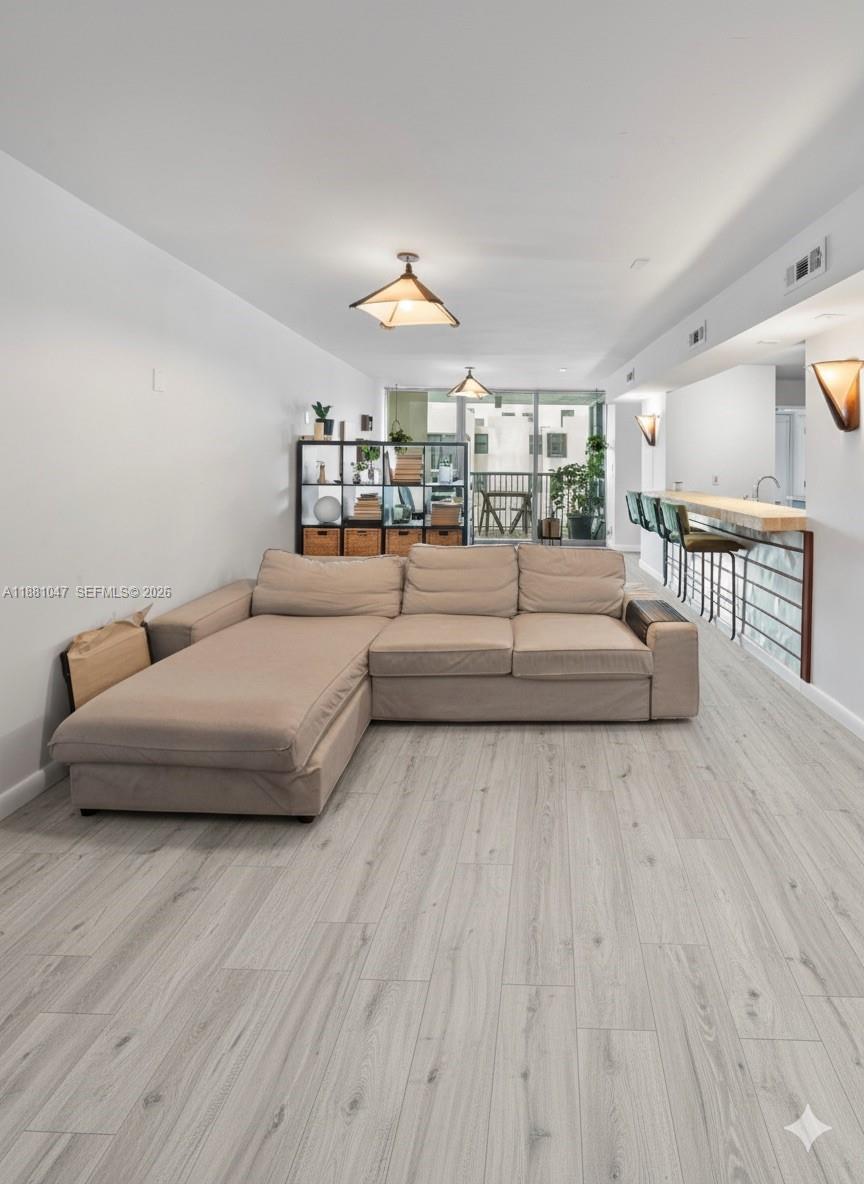 A living room features a beige sectional sofa, light wood-look flooring, and a breakfast bar — 2655 Collins Ave # 510, Miami Beach FL 33140, MIAMI BEACH, FL