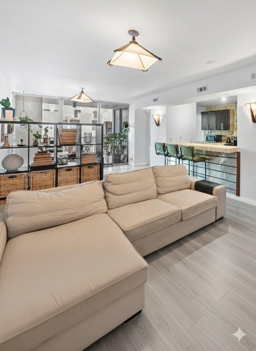A living room features a beige sectional sofa, a room divider, and a kitchen breakfast bar — 2655 Collins Ave # 510, Miami Beach FL 33140, MIAMI BEACH, FL