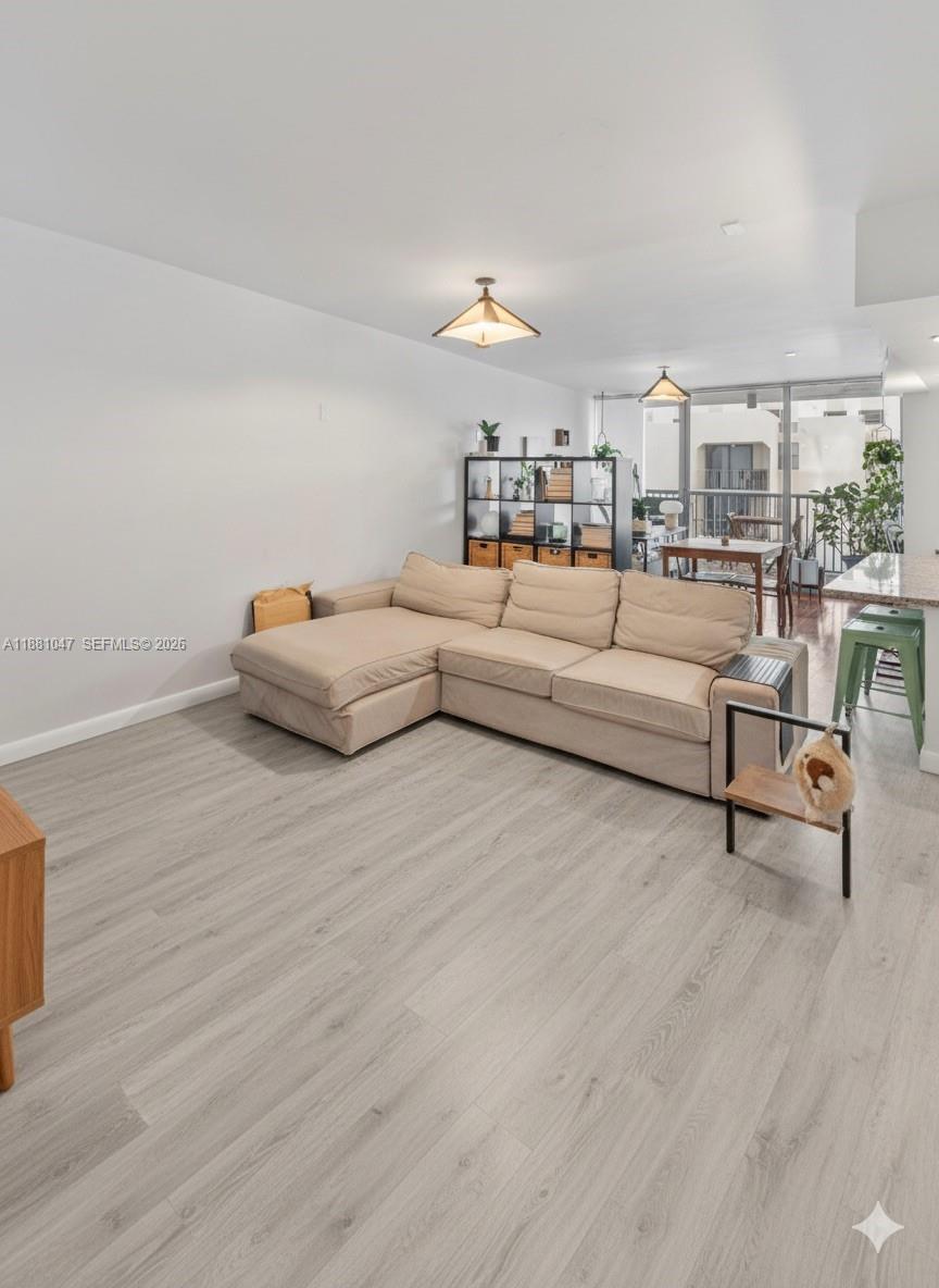 A living room features a beige sectional sofa, light wood-look flooring, and an open balcony — 2655 Collins Ave # 510, Miami Beach FL 33140, MIAMI BEACH, FL
