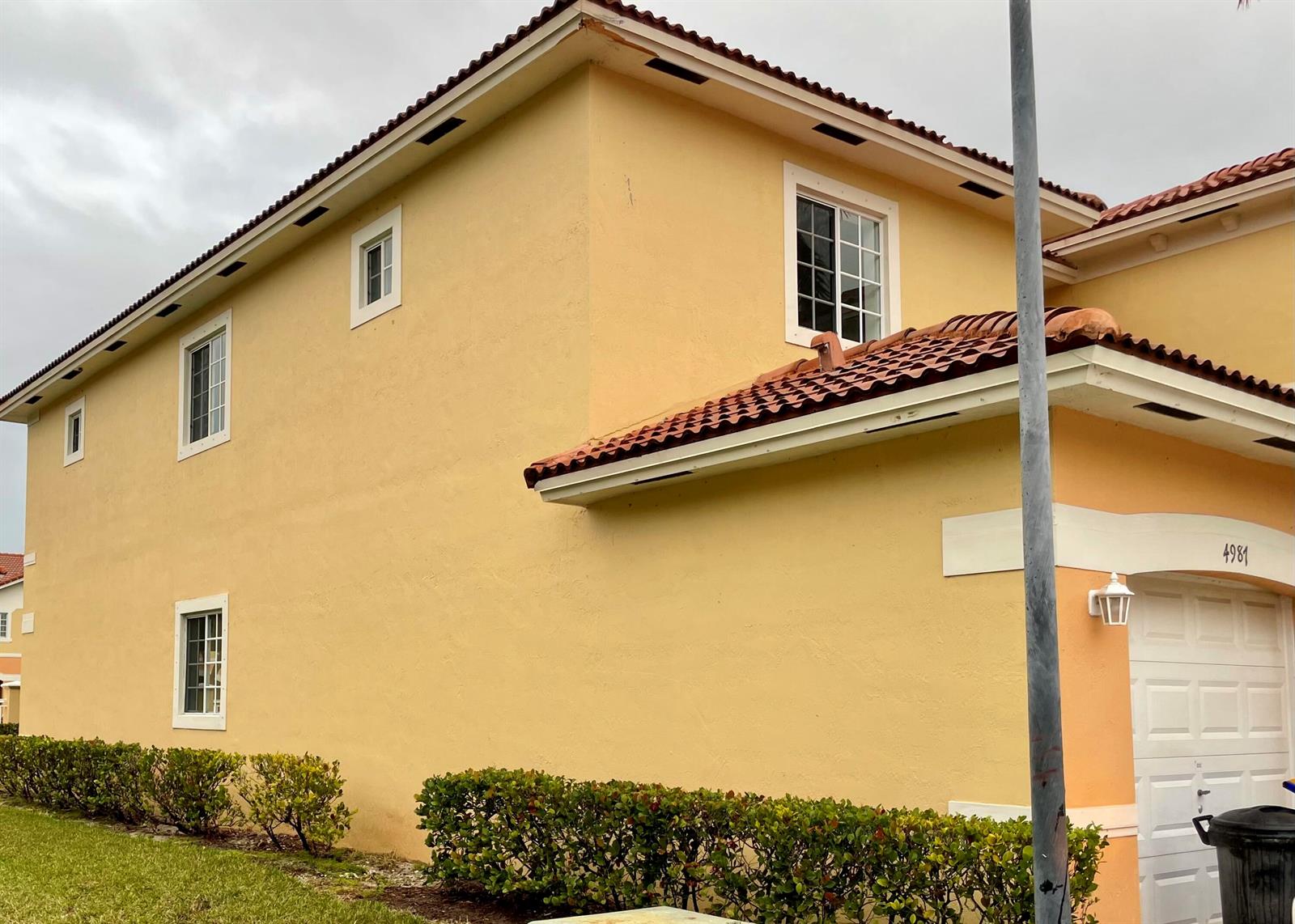 A two-story yellow stucco house with a tiled roof and a white garage door — 4987 SE Mariner Garden Circle, Stuart FL 34997, STUART, FL