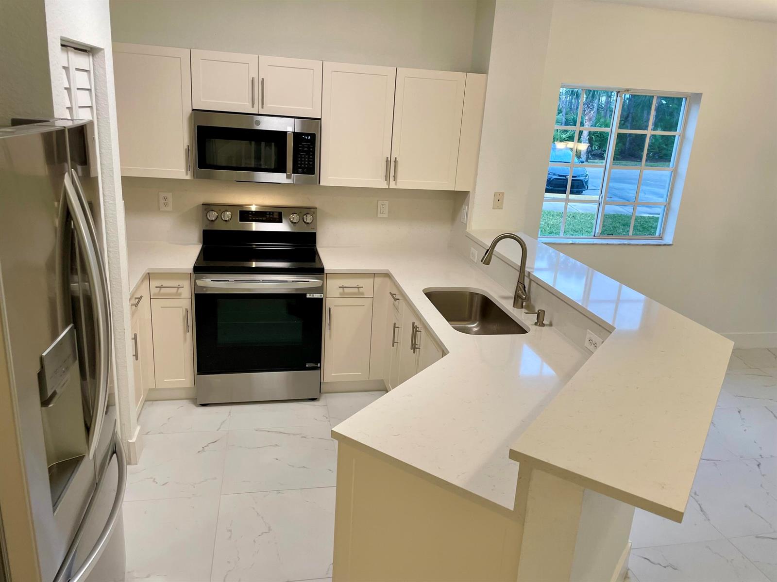 A kitchen with white cabinets, stainless steel appliances, and a peninsula countertop — 4987 SE Mariner Garden Circle, Stuart FL 34997, STUART, FL