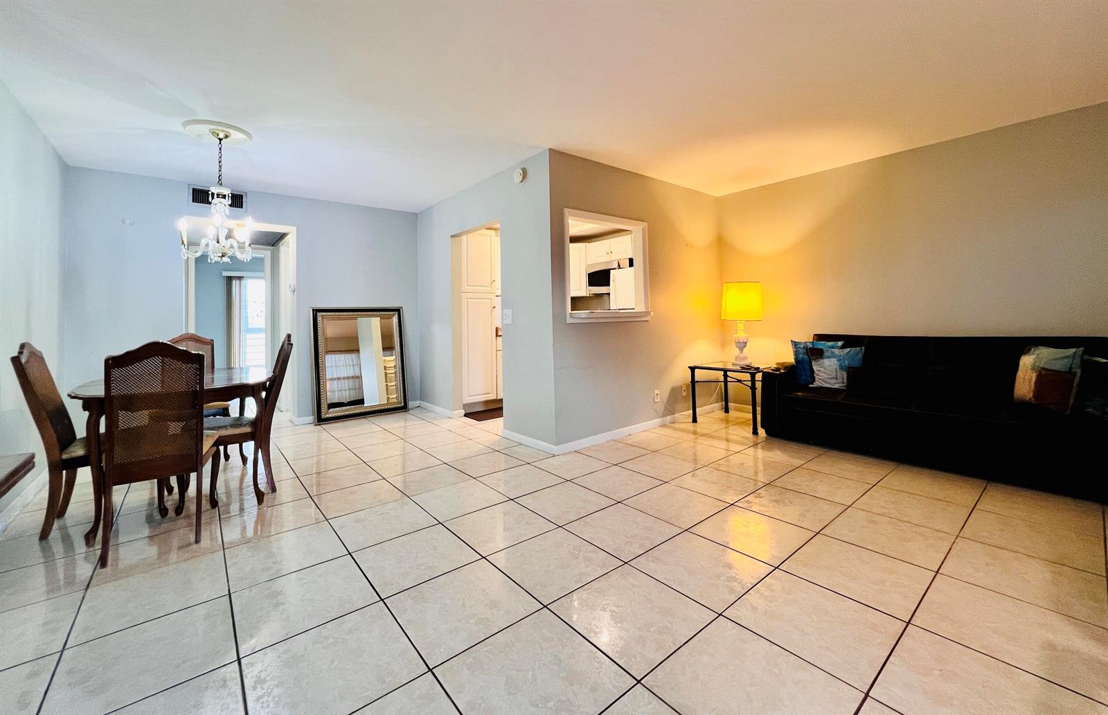An open-concept living and dining area features light-colored tile flooring and a dark sofa — 330 Southampton B, West Palm Beach FL 33417, WEST PALM BEACH, FL