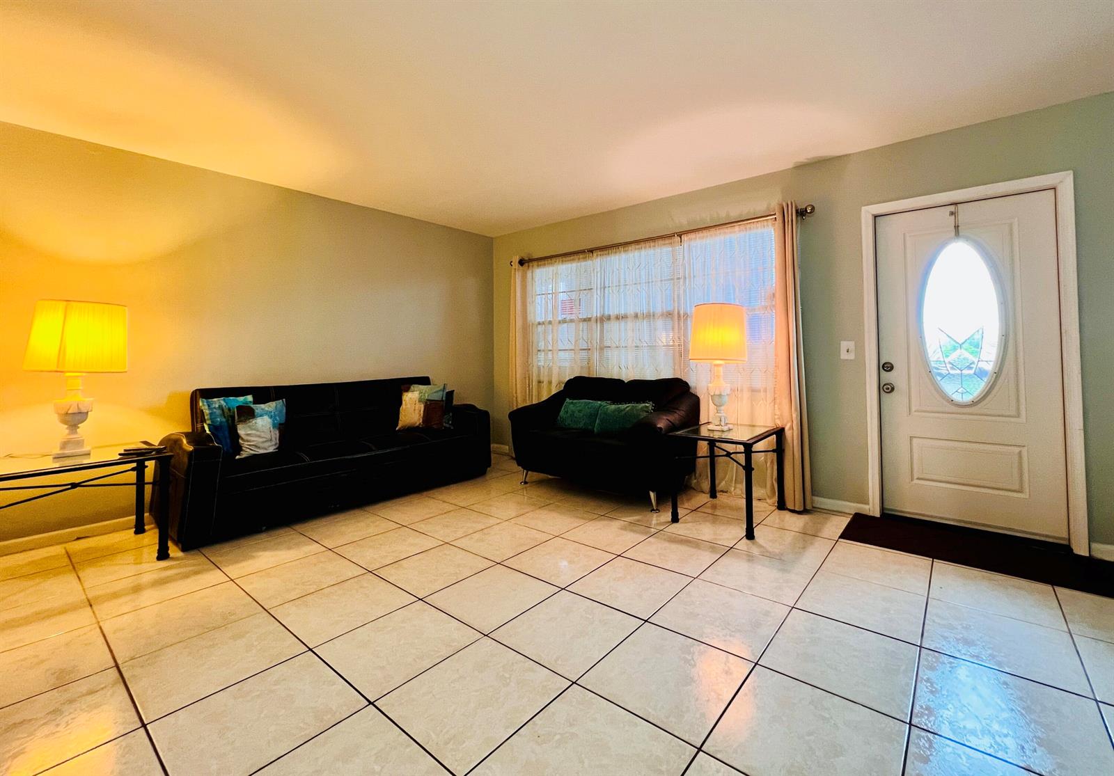 A living room features light-colored tile flooring, two black sofas, and a white front door — 330 Southampton B, West Palm Beach FL 33417, WEST PALM BEACH, FL