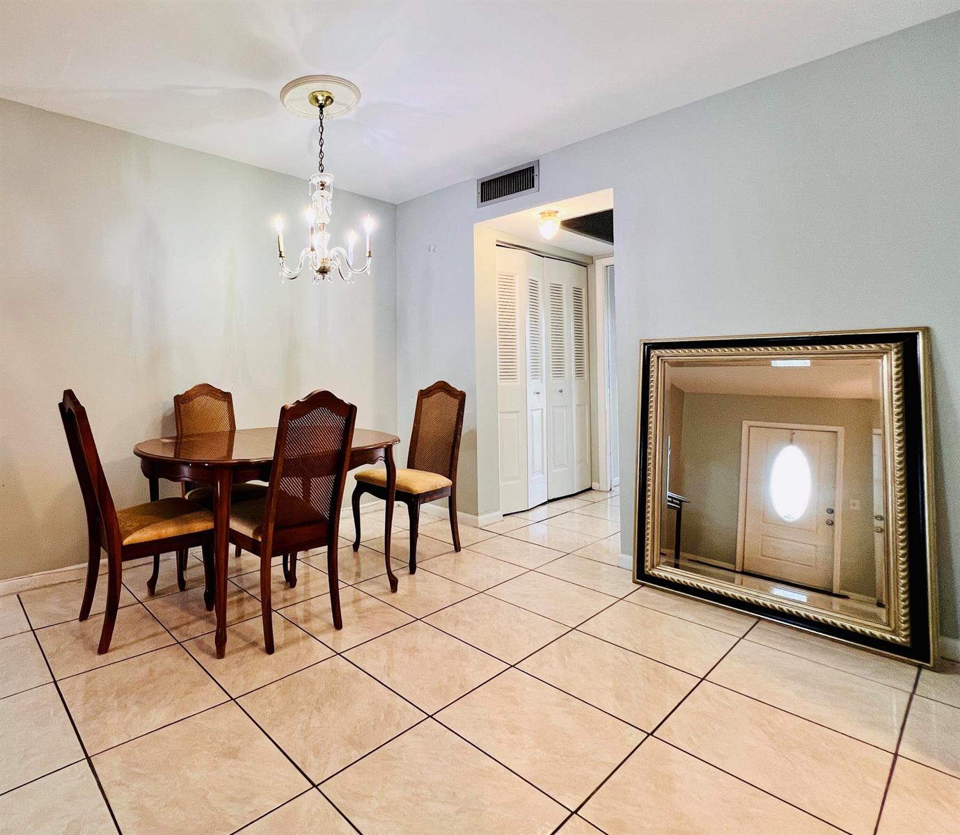 A dining area features a wooden table, four chairs, a crystal chandelier, and a large mirror — 330 Southampton B, West Palm Beach FL 33417, WEST PALM BEACH, FL