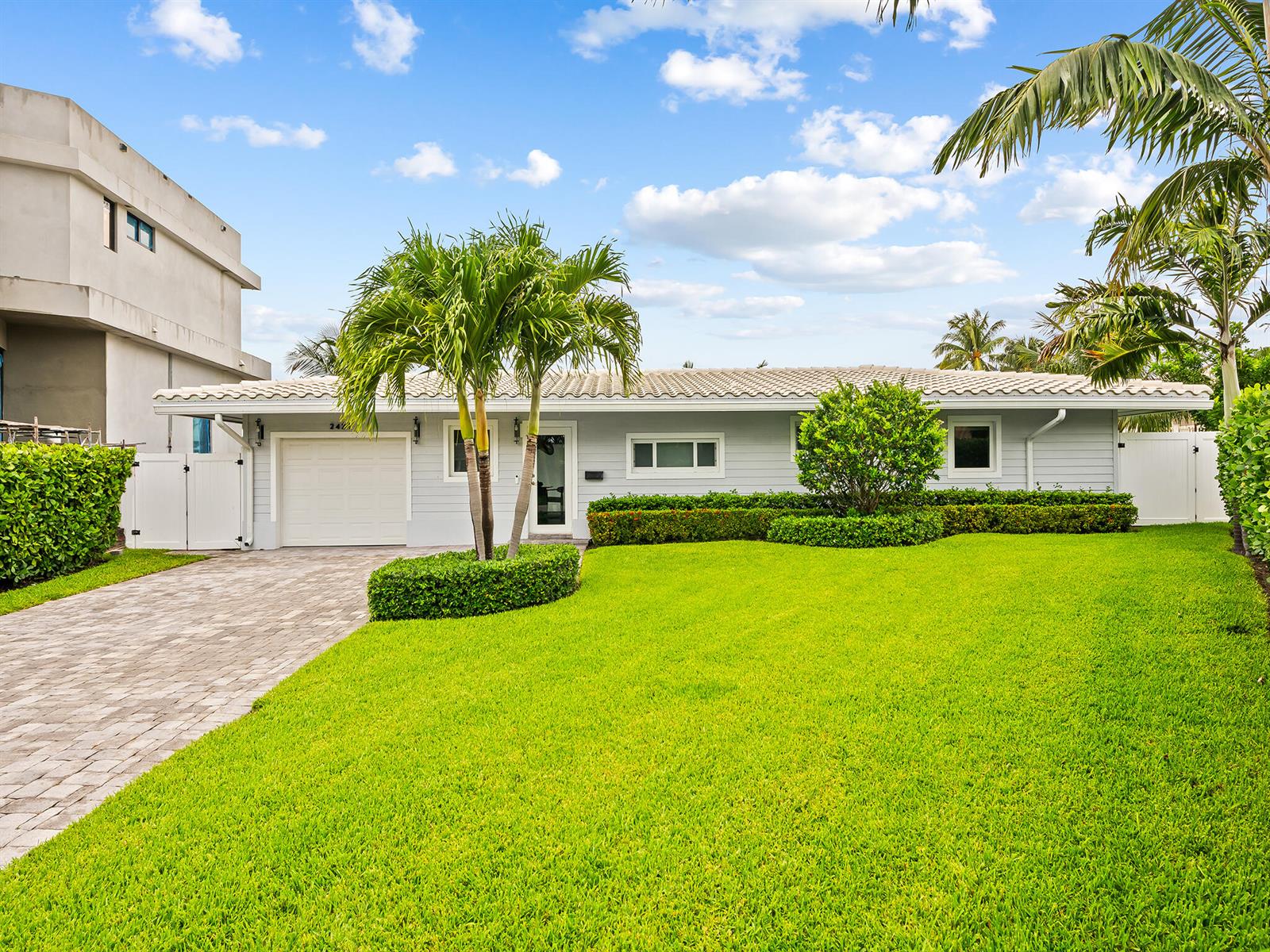 A single-story gray house with a tiled roof, a paved driveway, and a front lawn — 2421 NE 50th Street, Lighthouse Point FL 33064, LIGHTHOUSE POINT, FL
