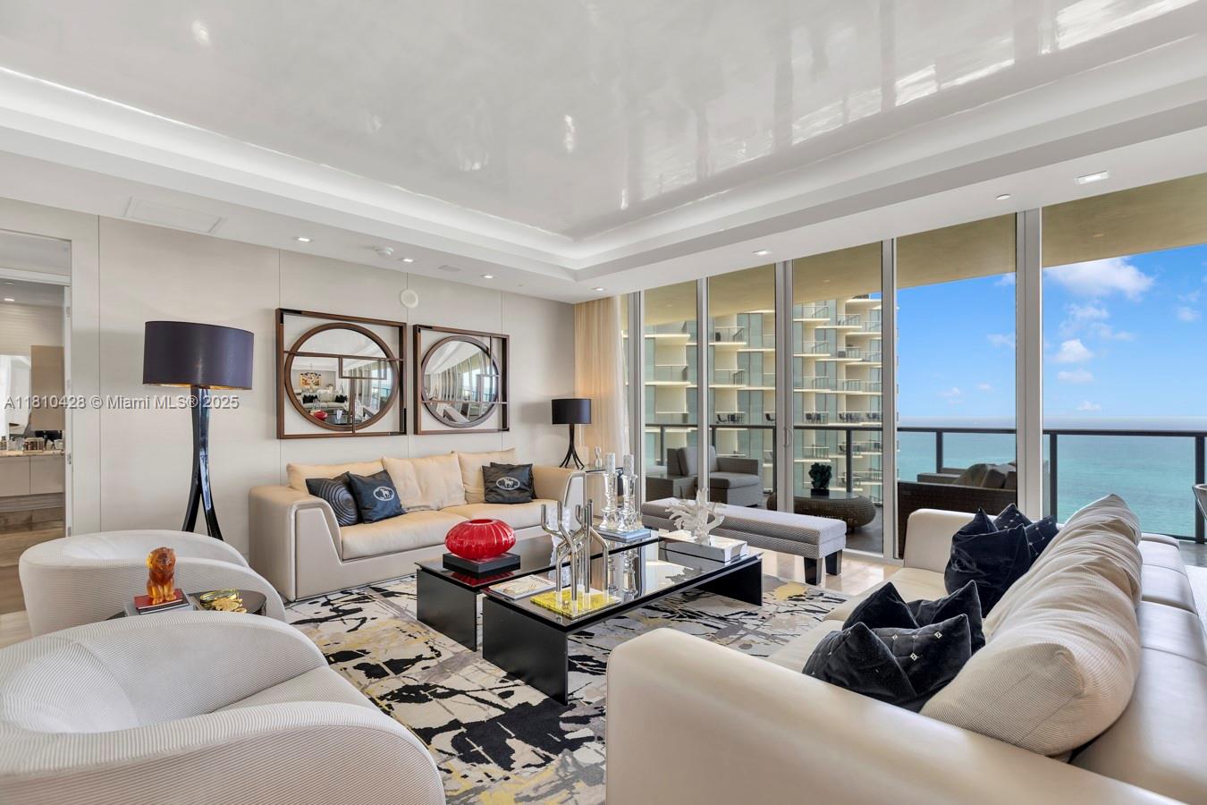 A modern living room features white sofas, a glass coffee table, and floor-to-ceiling ocean views — 9701 Collins Ave # 2403S, Bal Harbour FL 33154, BAL HARBOUR, FL