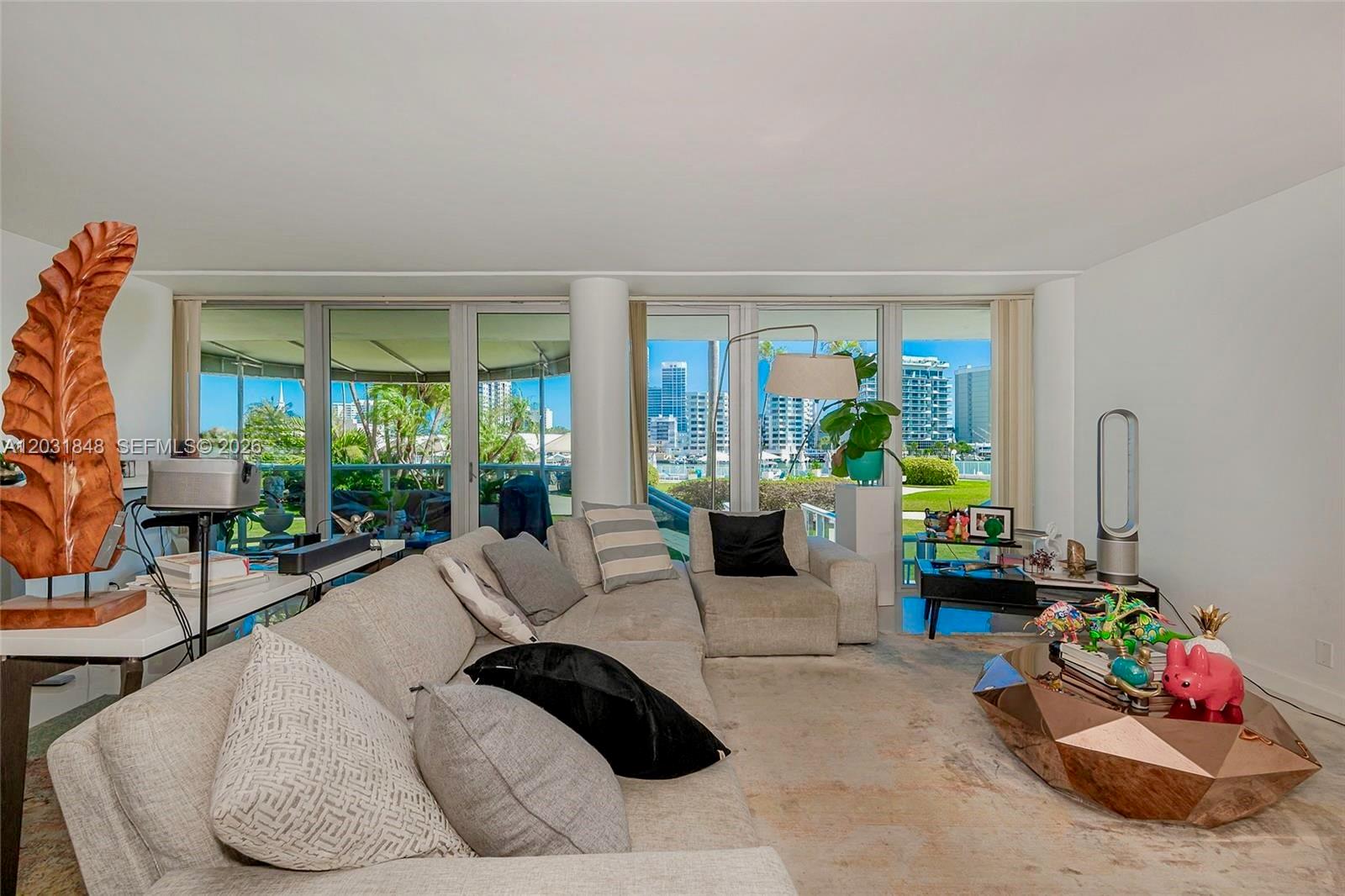 A living room features a large sectional sofa, a geometric coffee table, and floor-to-ceiling windows — 900 Bay Dr # 122, Miami Beach FL 33141, MIAMI BEACH, FL