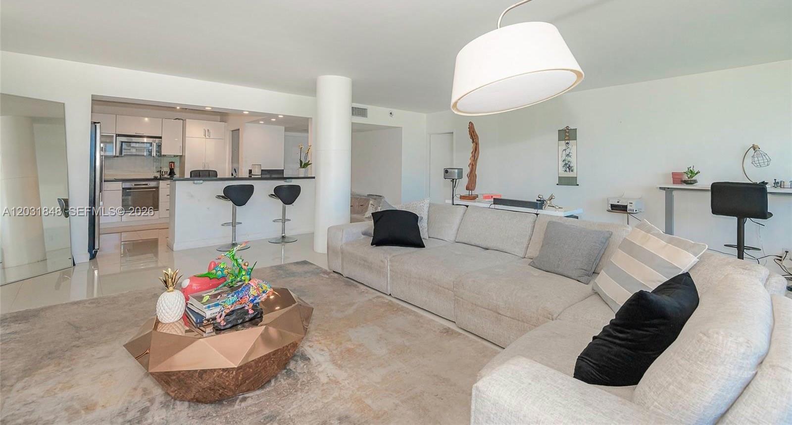 A living room features a sectional sofa, a geometric coffee table, and an open kitchen — 900 Bay Dr # 122, Miami Beach FL 33141, MIAMI BEACH, FL