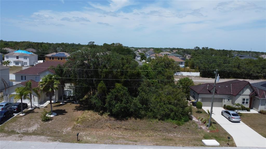 An aerial view shows a vacant, tree-covered lot situated between two residential houses — 315 CHURCHILL COURT, KISSIMMEE, FL