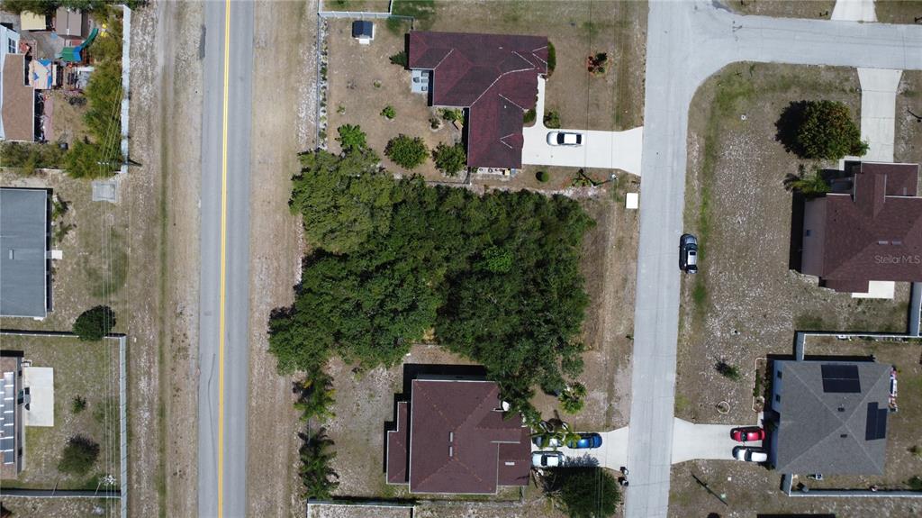 An aerial view shows a vacant, tree-covered residential lot situated between two houses and streets — 315 CHURCHILL COURT, KISSIMMEE, FL