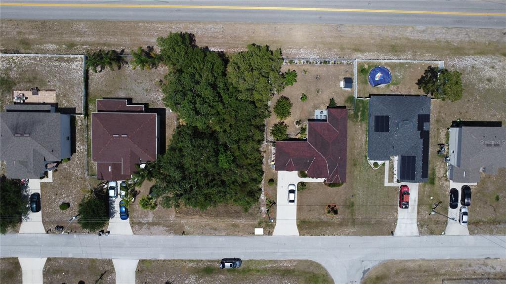 An aerial view shows a residential street with several houses and a vacant, tree-covered lot — 315 CHURCHILL COURT, KISSIMMEE, FL