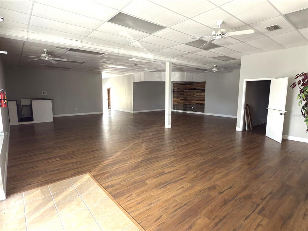 An open commercial space features wood-look flooring, a drop ceiling, and a wood-paneled accent wall — 3762 TAMIAMI TRAIL UNIT H, PORT CHARLOTTE, FL