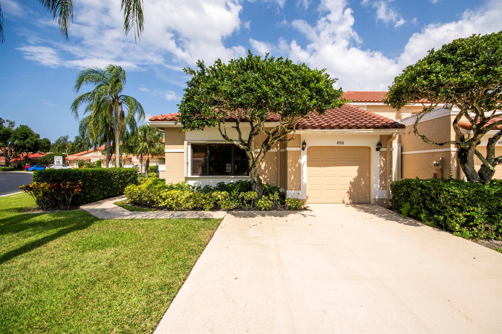 A single-story tan house with a tile roof, a garage, and a landscaped front yard — 850 Windermere Way, Palm Beach Gardens FL 33418, PALM BEACH GARDENS, FL