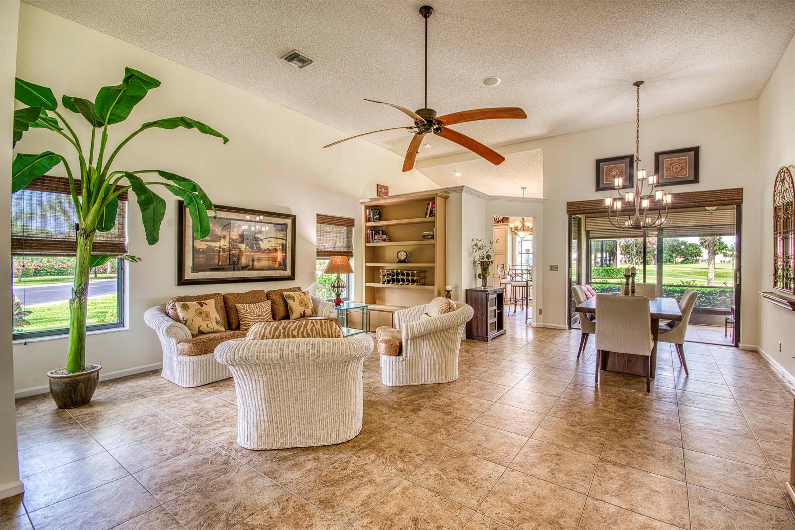 A bright living and dining area features tile flooring, wicker furniture, and a large potted plant — 850 Windermere Way, Palm Beach Gardens FL 33418, PALM BEACH GARDENS, FL