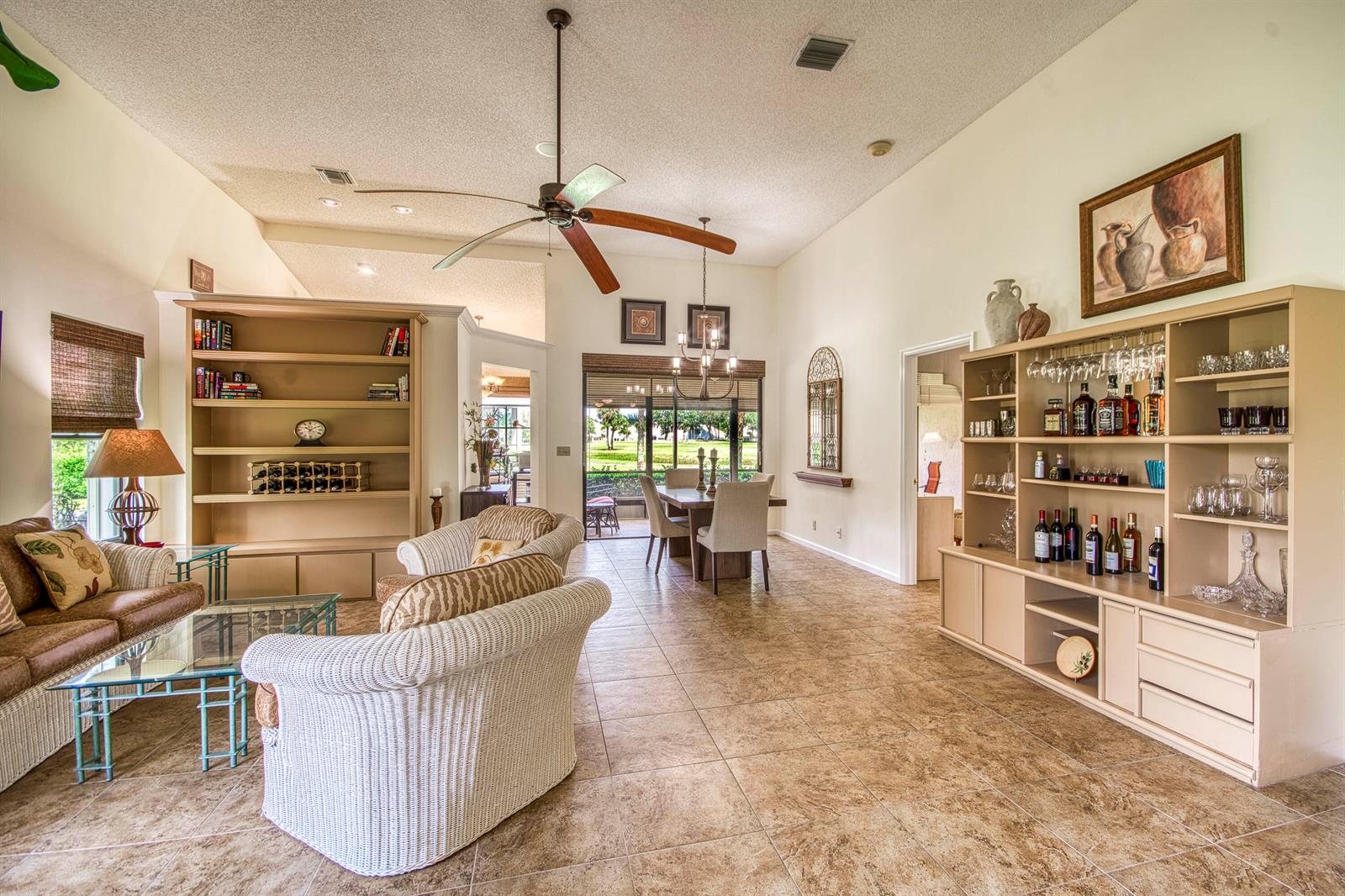 A bright living and dining area features tile floors, built-in shelving, and a ceiling fan — 850 Windermere Way, Palm Beach Gardens FL 33418, PALM BEACH GARDENS, FL