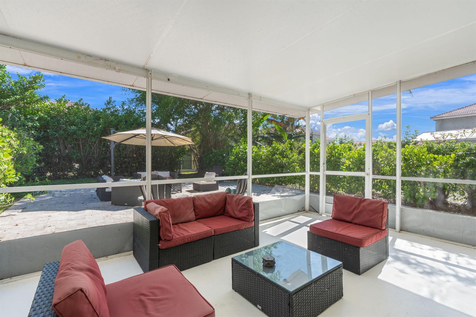 A screened-in patio features wicker furniture with red cushions and a glass-topped coffee table — 4846 Purdue Drive, Boynton Beach FL 33436, BOYNTON BEACH, FL