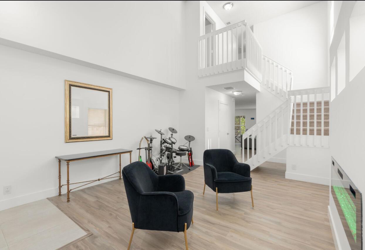 A living area with high ceilings, two dark armchairs, a console table, and a drum set — 4846 Purdue Drive, Boynton Beach FL 33436, BOYNTON BEACH, FL