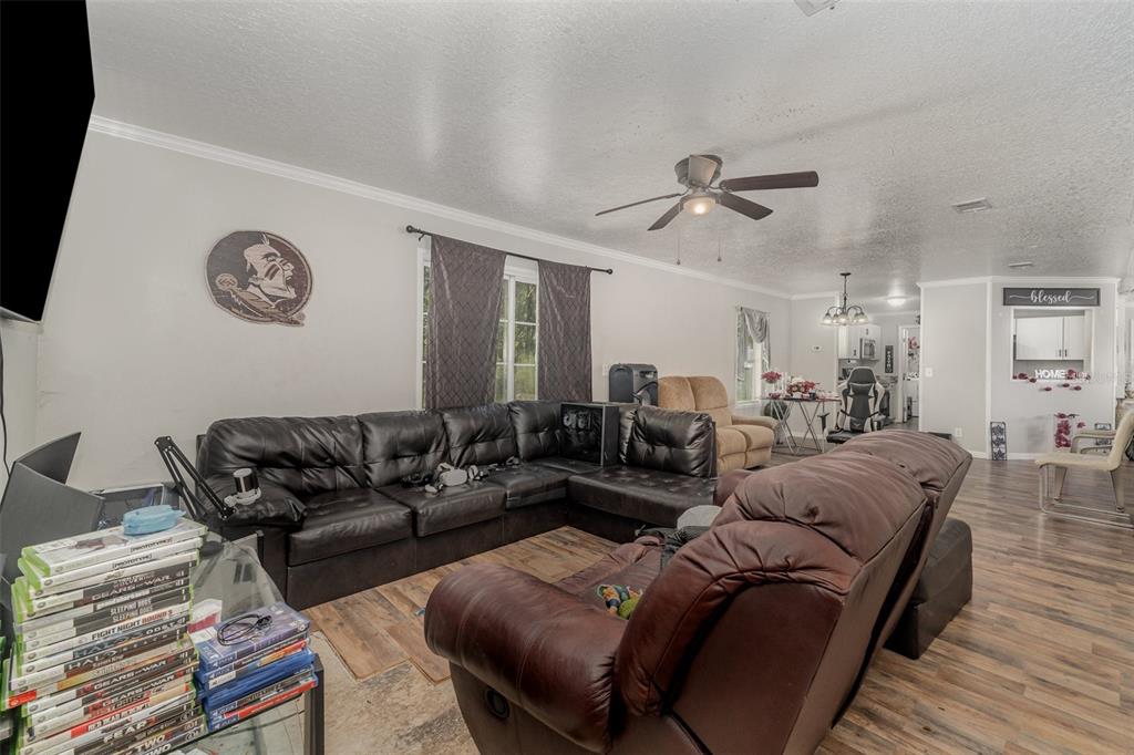 A living room features a large black sectional sofa, a brown recliner, and wood-look flooring — 18905 NW 250TH STREET, HIGH SPRINGS, FL