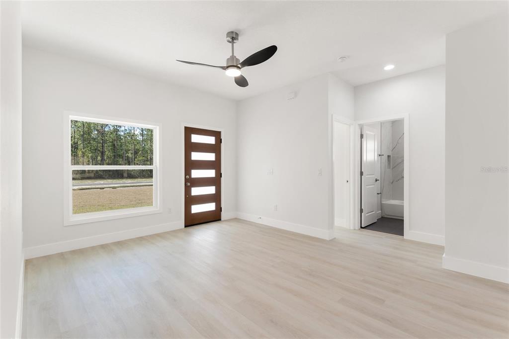 A bright room with light wood-look flooring, a ceiling fan, a window, and two doors — 3750 JAPONICA AVENUE, INDIAN LAKE ESTATES, FL