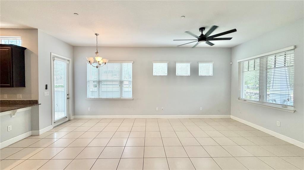 An open-concept dining area features light tile flooring, a ceiling fan, and multiple windows — 8348 TAVISTOCK LAKES BOULEVARD, ORLANDO, FL