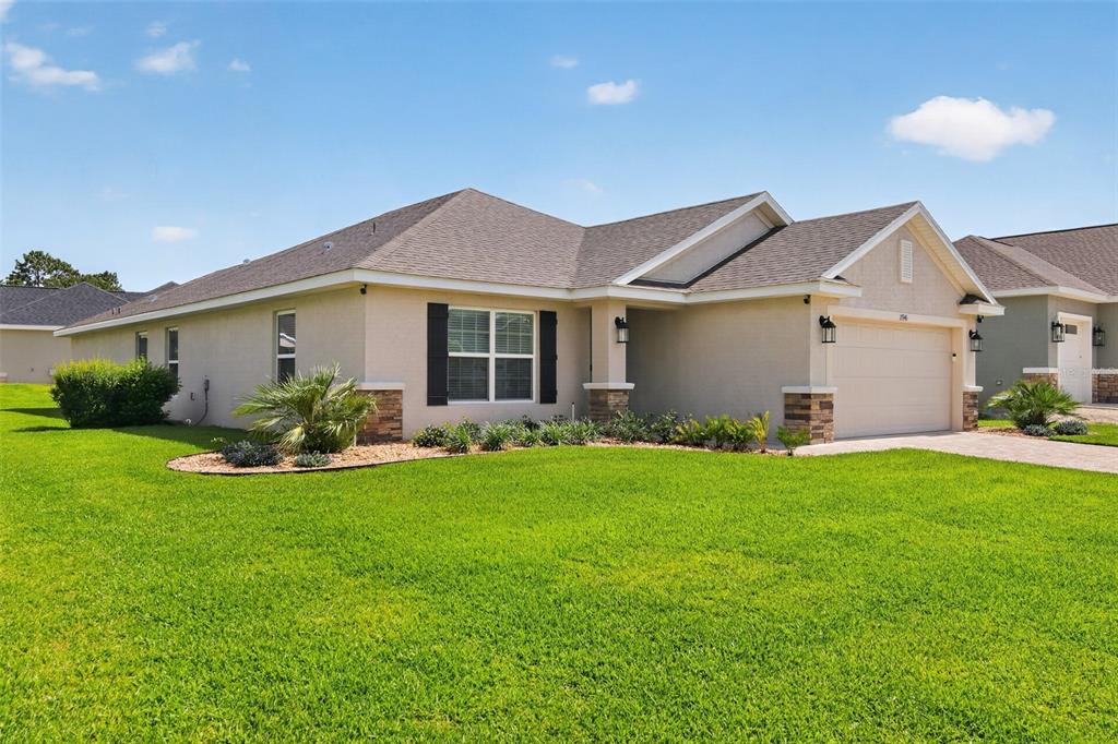 A single-story suburban house with a tan stucco exterior, stone accents, and a two-car garage — 17941 SW 66TH PLACE, DUNNELLON, FL
