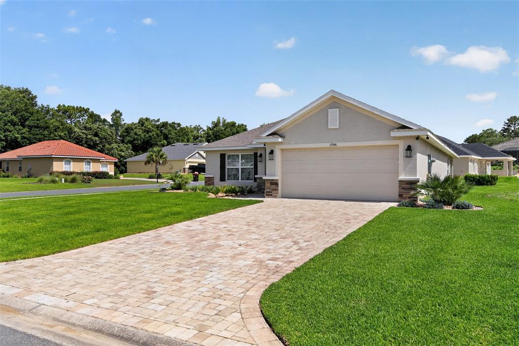 A single-story house with a beige stucco exterior, a paved driveway, and a two-car garage — 17941 SW 66TH PLACE, DUNNELLON, FL