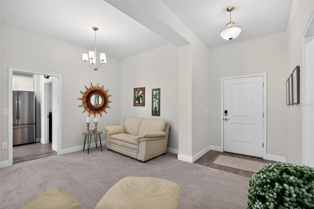 A living area features a beige sofa, a sunburst mirror, and a white front door — 17941 SW 66TH PLACE, DUNNELLON, FL