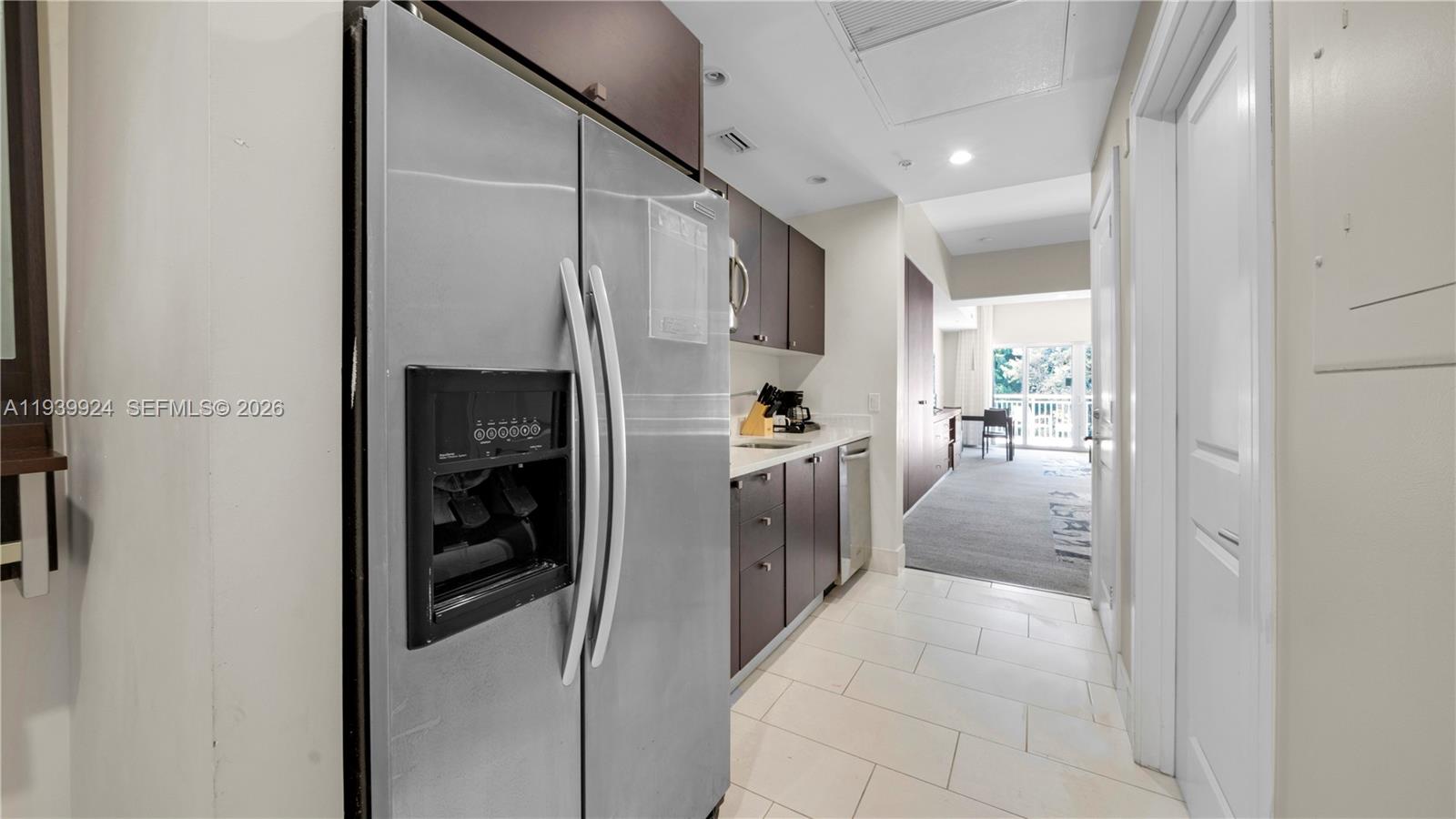 A galley kitchen features stainless steel appliances, dark wood cabinets, and light tile flooring — 5300 NW 87th Ave # 1510, Doral FL 33178, DORAL, FL