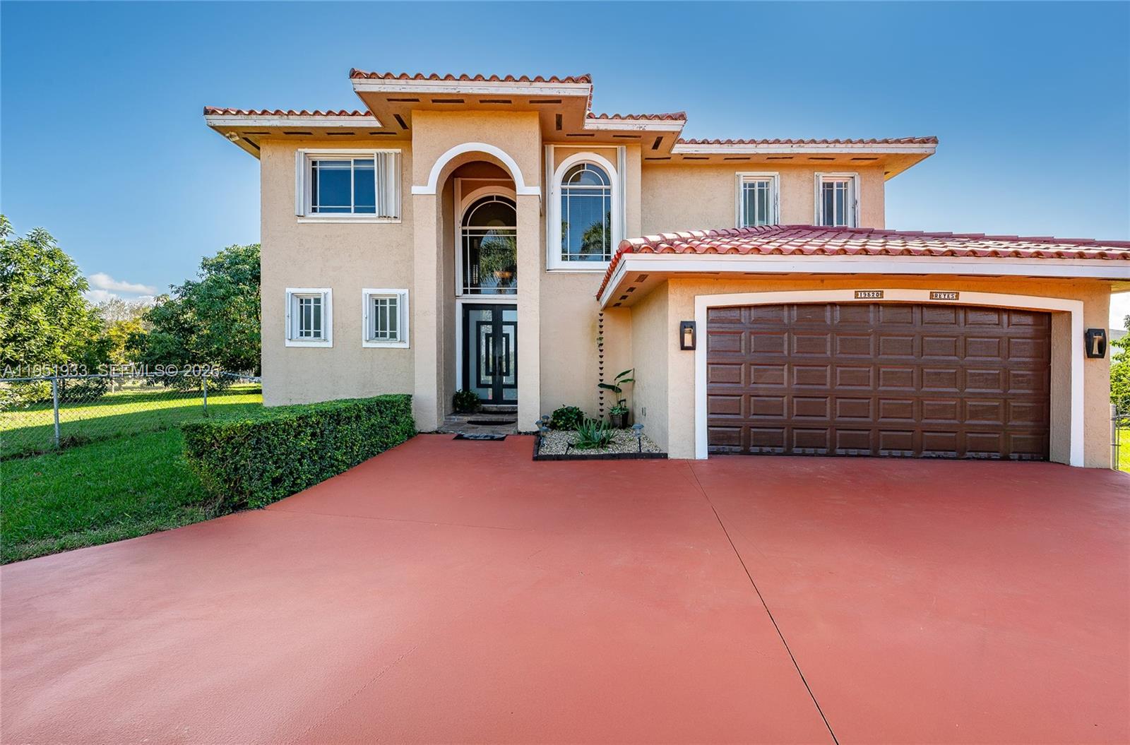 A two-story stucco house features a red-tiled roof, a brown garage door, and a driveway — 19520 SW 206th St, Miami FL 33187, MIAMI, FL