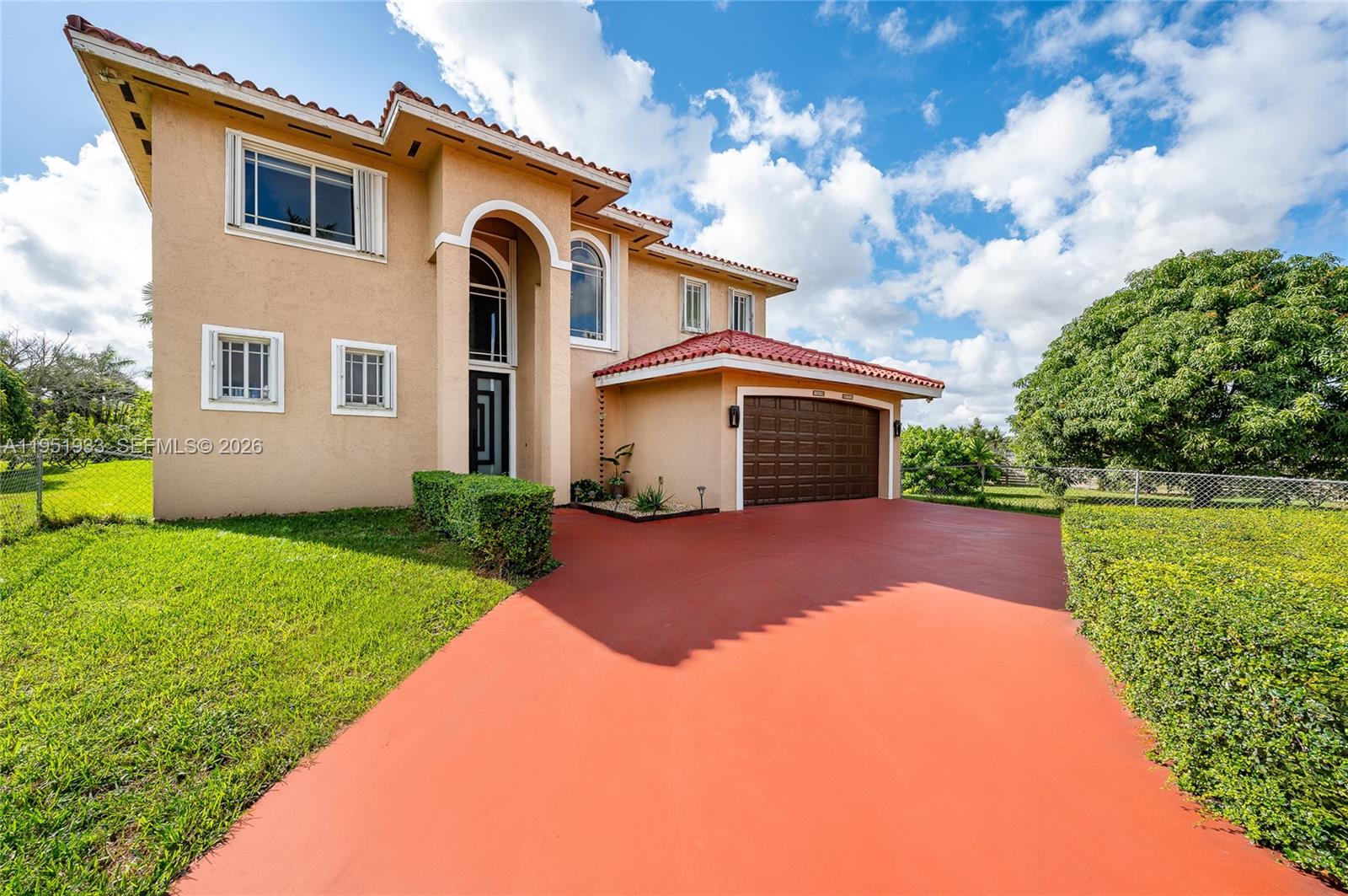 A two-story house with a red-tiled roof and a red driveway under a blue sky — 19520 SW 206th St, Miami FL 33187, MIAMI, FL