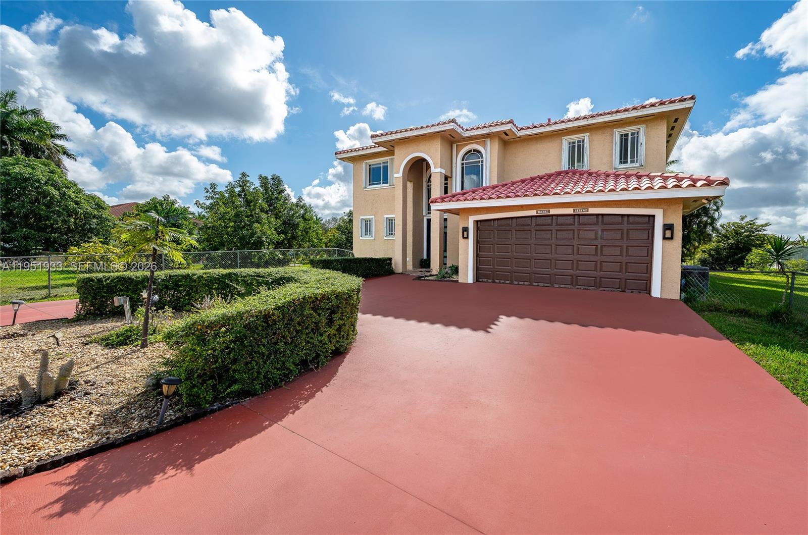 A two-story stucco house features a red tile roof and a large brown garage door — 19520 SW 206th St, Miami FL 33187, MIAMI, FL
