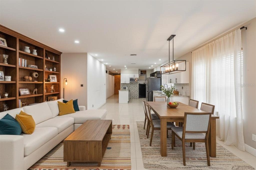 An open-concept living and dining area features a large bookshelf, sectional sofa, and kitchen — 1829 5TH, MIAMI, FL