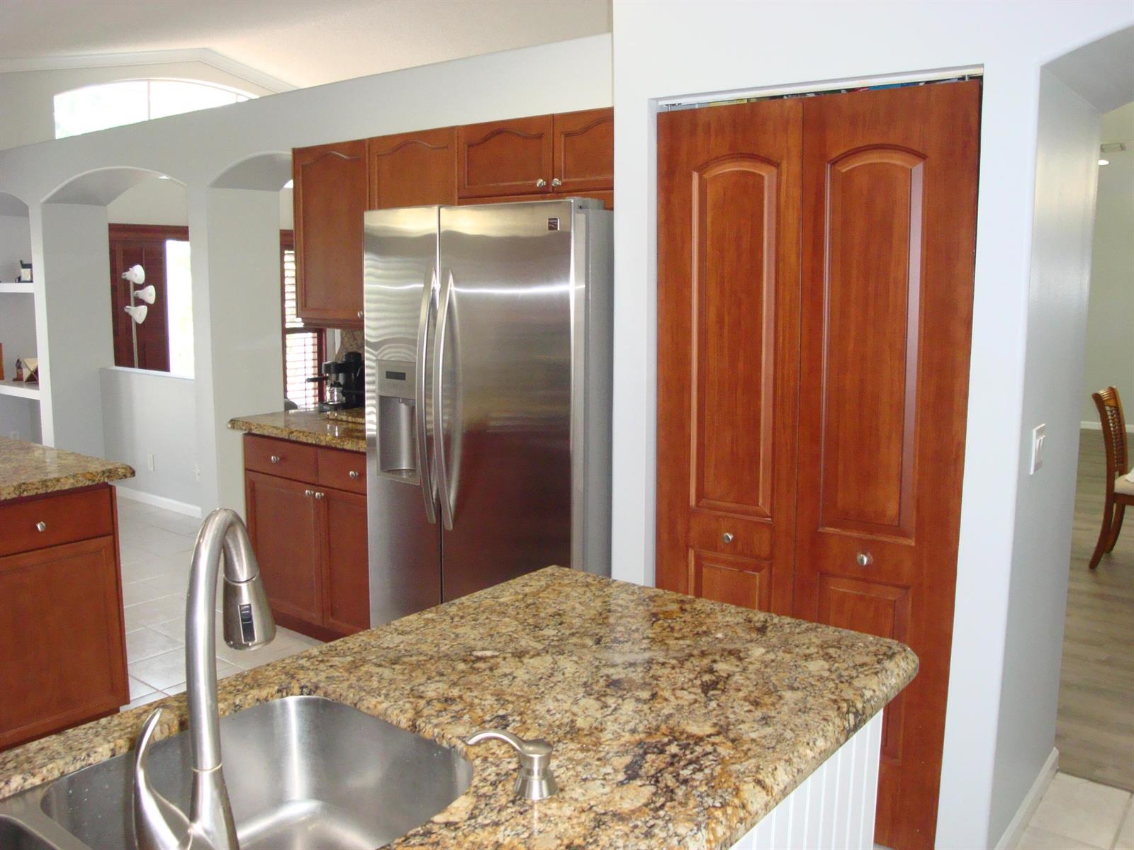 A kitchen features granite countertops, stainless steel appliances, and wood cabinetry — 6304 Barton Creek Circle, Lake Worth FL 33463, LAKE WORTH, FL
