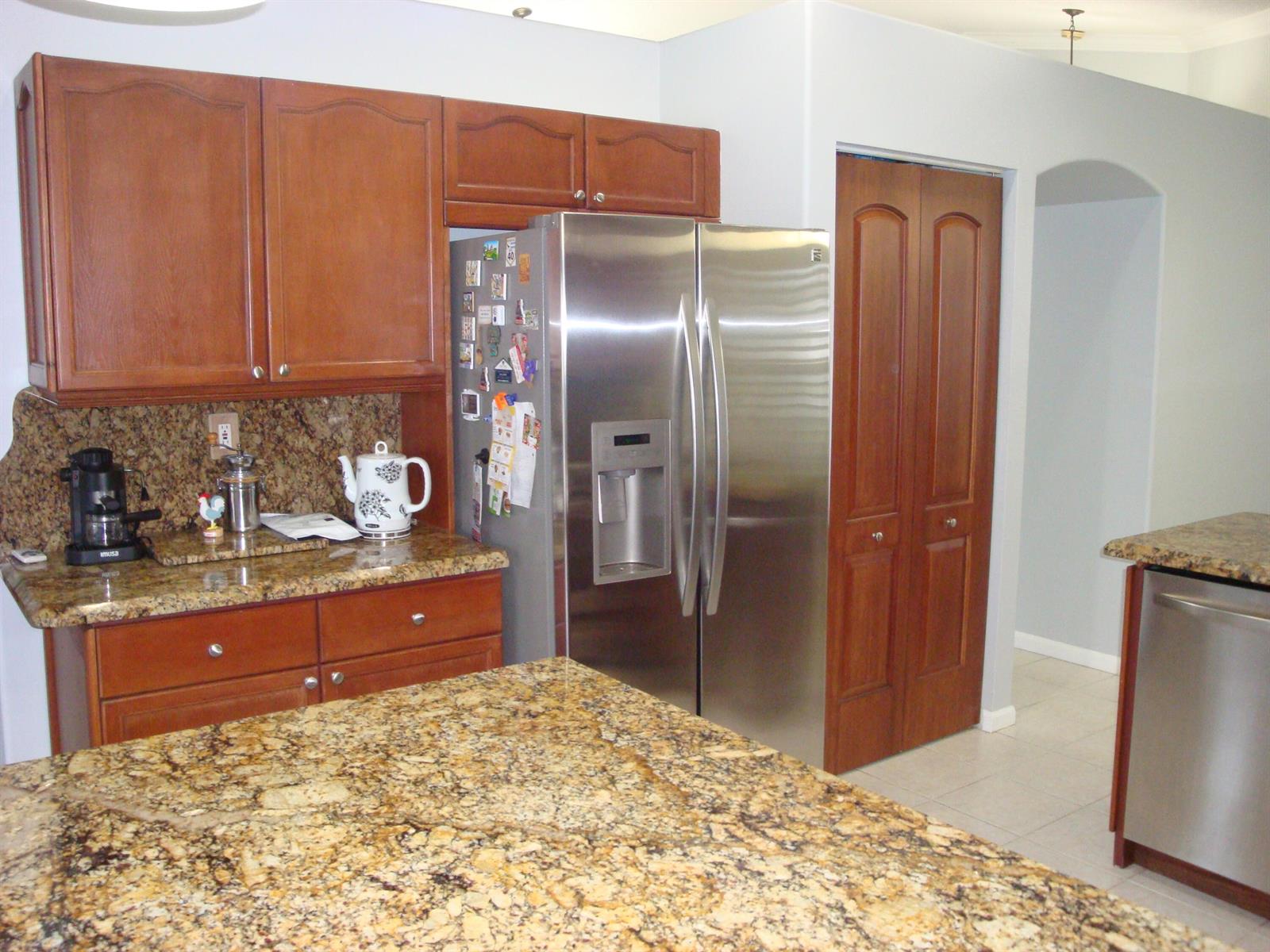 A kitchen featuring wood cabinets, granite countertops, stainless steel appliances, and a central island — 6304 Barton Creek Circle, Lake Worth FL 33463, LAKE WORTH, FL