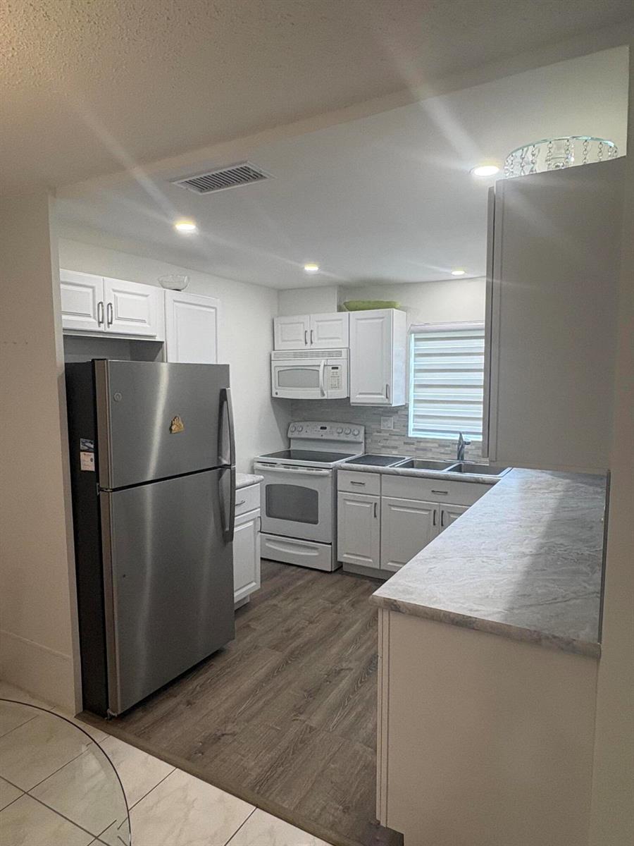 A kitchen features white cabinets, stainless steel appliances, and gray faux-marble countertops — 2522 Emory Drive E # A, West Palm Beach FL 33415, WEST PALM BEACH, FL