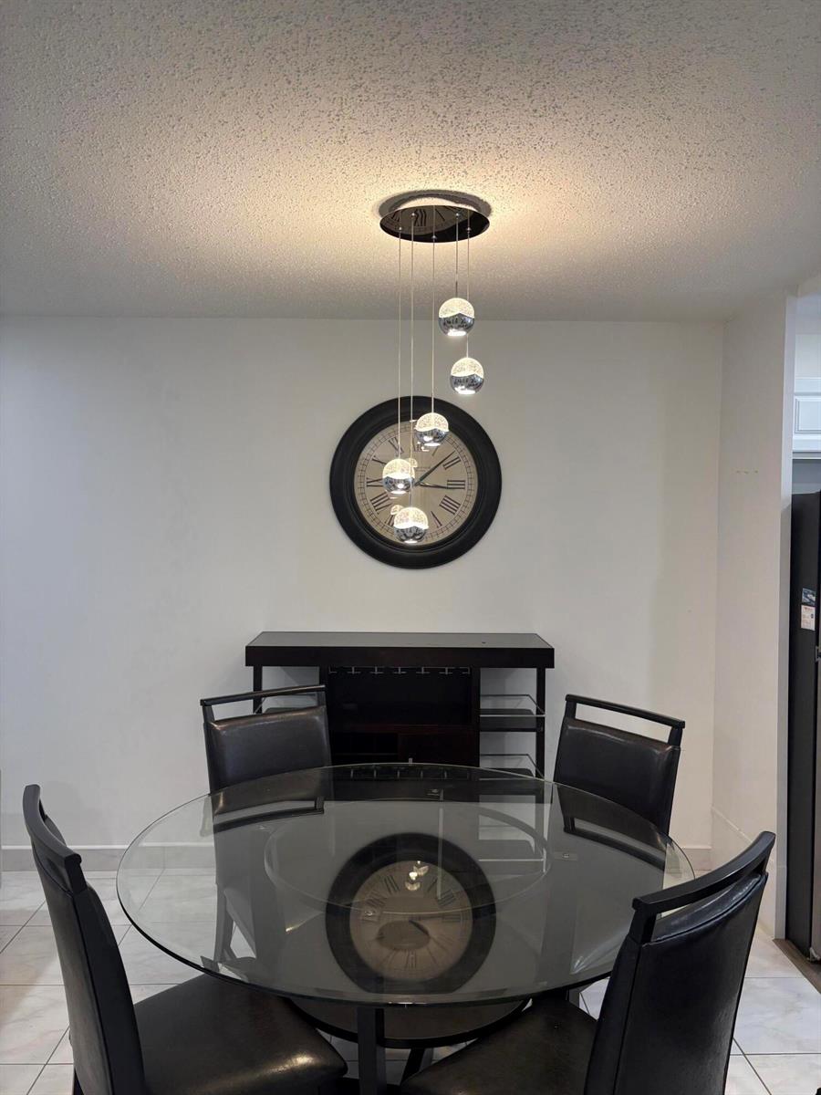 A dining room features a glass-topped table, black chairs, a wall clock, and pendant lighting — 2522 Emory Drive E # A, West Palm Beach FL 33415, WEST PALM BEACH, FL