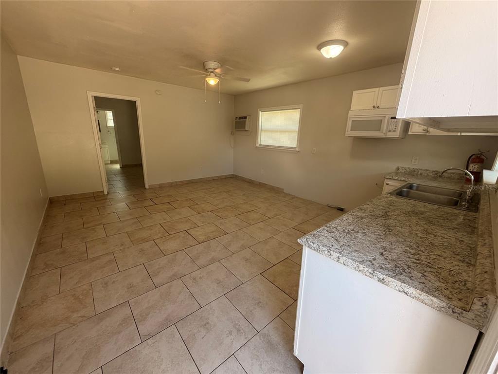 A kitchen with granite countertops and tile flooring opens into a living area — 110 FOREST AVENUE UNIT 8, DAVENPORT, FL