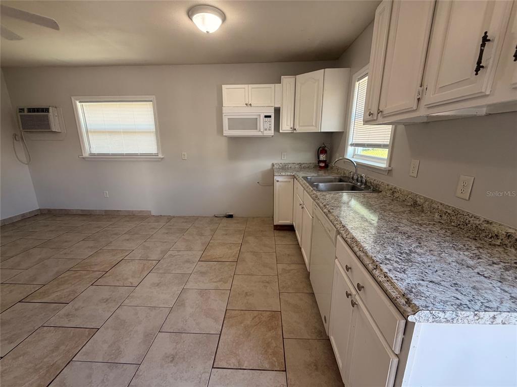A kitchen features white cabinets, granite countertops, a double sink, and tiled flooring — 110 FOREST AVENUE UNIT 8, DAVENPORT, FL