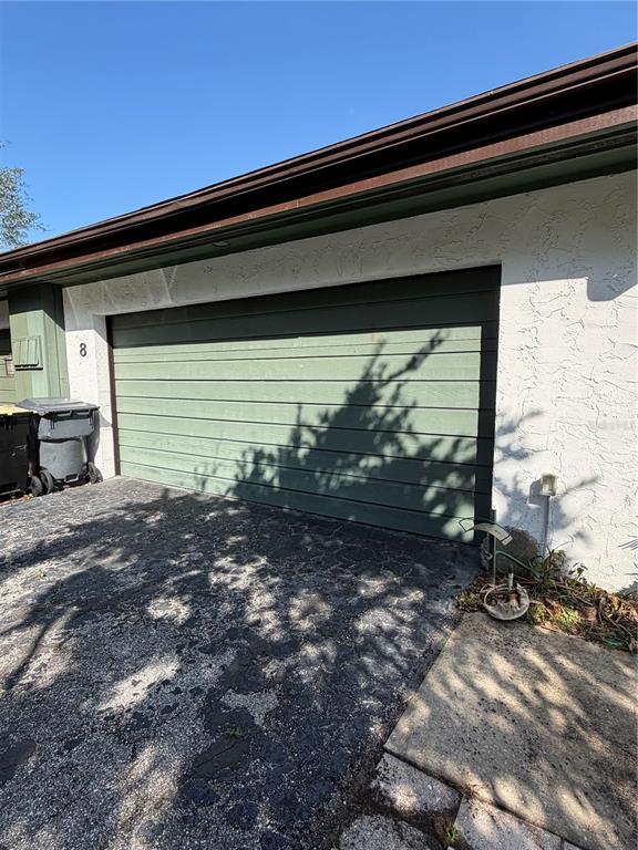 A green garage door is attached to a white stucco building with a dark roof — 8 CANTERBURY DRIVE, HAINES CITY, FL
